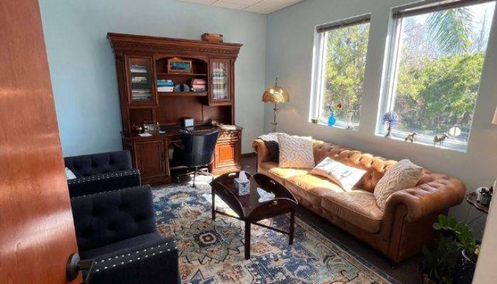 Picture of a Therapist Office in Stuart, Florida with wooden desk, brown couch, and blue chairs.